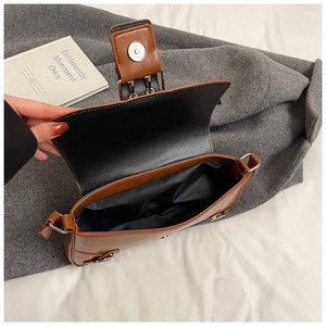 Internal view of brown punk rivet shoulder bag showing magnetic buckle and storage capacity
