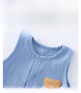 Detail of light blue breathable cotton gauze baby romper with brown bear patch and buttons