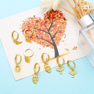 Detail of gold owl bird flower and feather wing earring set with zircon accents