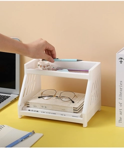 Macro view of white 2-tier plastic desk organizer holding stationery on yellow table
