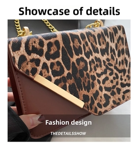 Detail of leopard print stitching and gold metal bar on brown leather shoulder bag