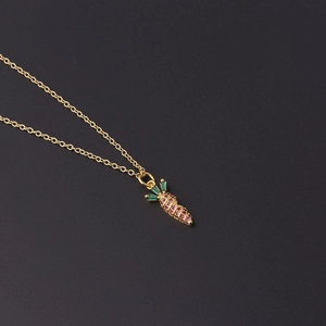 Detailed close-up of a gold carrot pendant necklace featuring pink and green zircon stones