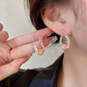 Nahaufnahme von eleganten Perlen-Silberohrringen mit rosa Kugelanhänger am weiblichen Model