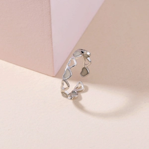 Detail of adjustable silver open ring featuring a series of cutout enamel heart shapes