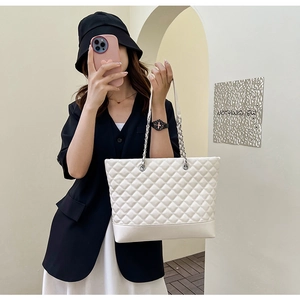 Grand sac cabas matelassé blanc cassé avec bandoulière chaîne argentée porté par un mannequin