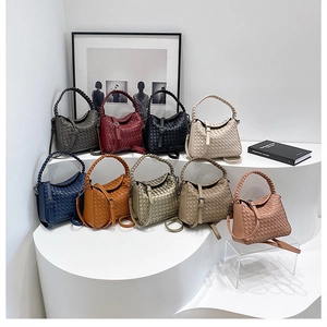 Multiple colors of hand-woven bucket bags displayed on an artistic white pedestal