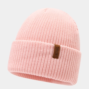 Detail of light pink ribbed knit beanie featuring a brown leather label with IACUGGL text