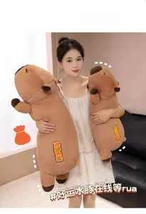 Detail of soft capybara plush pillow with orange embroidery shown held by a person