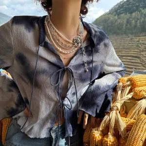 Detail of layered pearl necklace with silver lion pendant and pleated tie-dye top