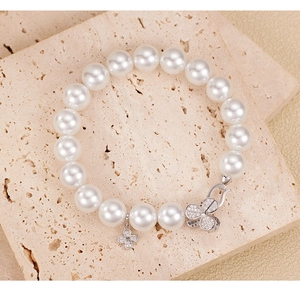 Macro shot of a 925 silver clover pearl bracelet with rhinestones on a stone surface