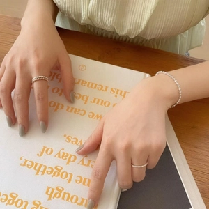 Detail of minimalist 2mm silver bead bracelet and matching rings on model hand