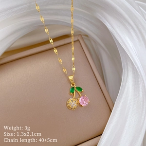 Detail of gold cherry pendant with pink and green zircon on jewelry box, weight 3g