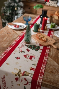 Cozy Christmas table runner with snowman and reindeer patterns on a wooden dining table