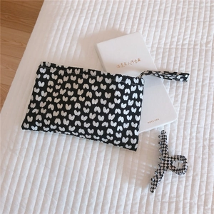 Detailed view of butterfly print canvas clutch bag and checkered hair claw clip