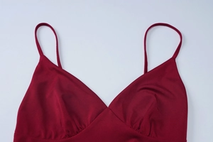 Detail of burgundy backless dress showing V-neckline, thin straps and ruched fabric texture