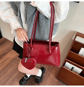 Close-up of red glossy patent leather tote bag with heart-shaped coin purse attachment