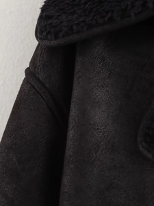Gros plan du col en peau de mouton bouclée et texture daim mat sur la veste noire