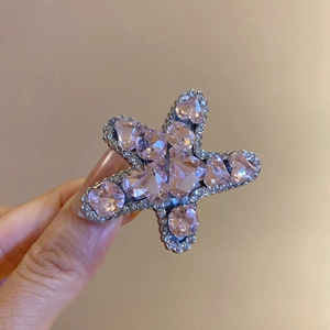 Detailed close-up of a pink rhinestone star hair clip held by hand with sparkling stones