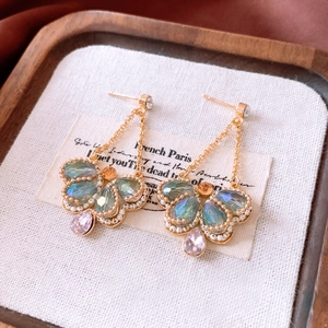 Detail of vintage teardrop earrings with colorful crystals and gold tassel on fabric