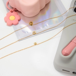 Detail of three-layer gold-plated necklaces with cubic zirconia ring pendants on props