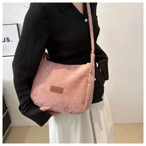 Detail of pink corduroy tote bag featuring a leather fashion label and zipper closure