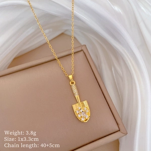 Macro view of gold shovel pendant with sparkling cubic zirconia on a necklace chain