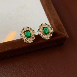 Gros plan sur des boucles d'oreilles losanges plaquées or avec zircon vert et cristaux