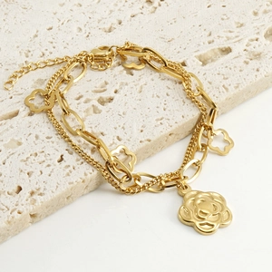 Detailed macro view of a gold rose double-layer bracelet on a textured stone display