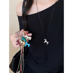 Detail view of multi-colored pony pendant necklaces with minimalist black cords on model