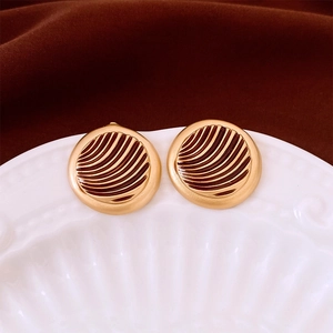 Macro view of vintage gold round earrings with textured radial grooves on ceramic plate