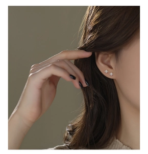 Close-up of minimalist S999 sterling silver star stud earrings worn on a female ear