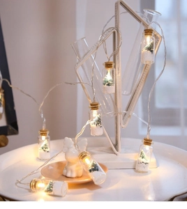 Close-up of LED glass wishing bottles with mini Christmas trees and artificial snow