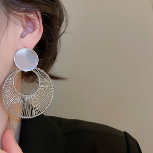 Silver geometric round hollow earring worn by model showing wire-wrapped metallic texture