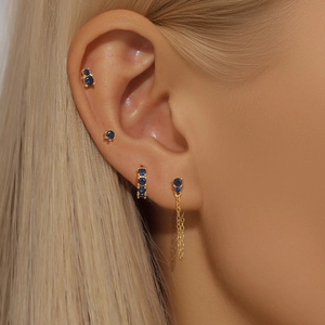 Macro shot of gold S925 sterling silver earrings set with blue gems on woman ear
