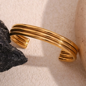 Detailed close-up of triple-layered 18K gold-plated cuff bracelet on natural stone base