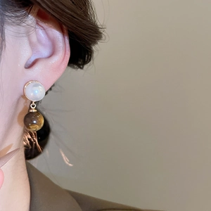 Detail shot of vintage pearl and amber resin ball pendant earrings worn on ear
