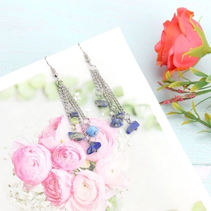 Close-up of bohemian silver chain earrings with natural blue crystal stone tassels