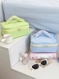 Detail of fluffy cloud handles with pink embroidery on blue and green makeup bags