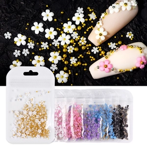 Close-up of resin flower nail charms and metallic beads in retail plastic pouches