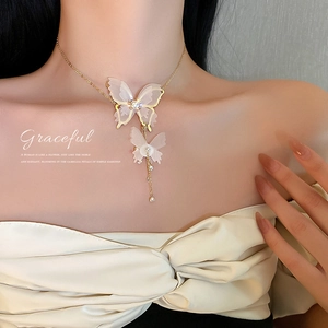 Close-up of golden butterfly necklace with pearl accents and tassels on a model