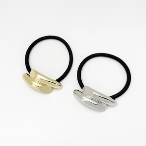 Detail of high-elastic black hair ties featuring gold and silver arched metal tubes