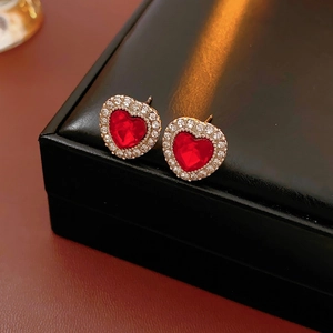 Primo piano di orecchini a cuore vintage con pietre preziose rosse e cristalli