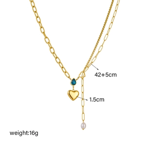 Golden double layer necklace with blue drop gem, heart pendant and pearl on white background