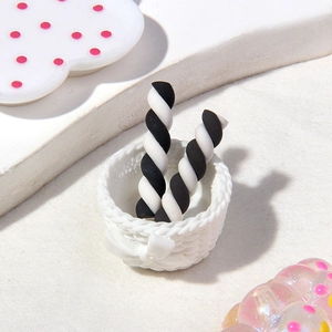 Close-up of black and white spiral resin stud earrings in a white woven basket