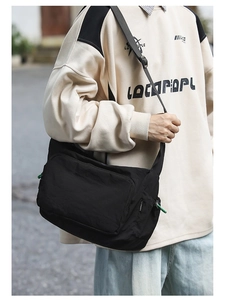Outdoor shot showing the practical use of a black waterproof nylon messenger bag for students