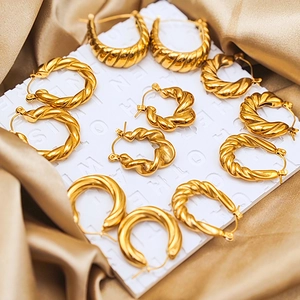 Macro shot of assorted gold twisted and croissant hoop earrings on a luxury silk backdrop