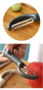 Detail of grey kitchen peeler slicing tomato skin with sharp stainless steel blade