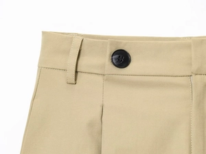 Dettaglio dei pantaloni in twill kaki con passanti per cintura, bottone nero e cuciture