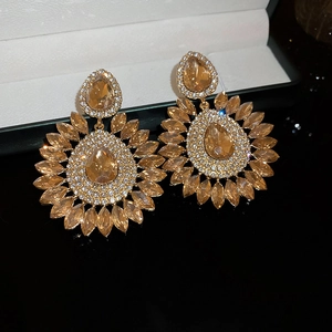 Macro shot of gold floral earrings with champagne crystals reflecting on a black surface