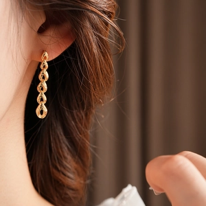 Détail de boucles d'oreilles épi de blé doré avec chaîne à pampilles sur modèle